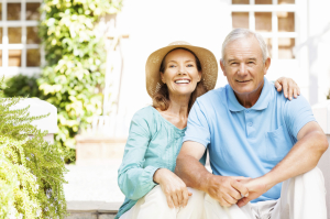 Happy Senior Woman Siting Arm Around Man In Yard